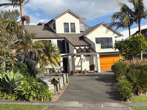 Et moderne hus med to etager, skråt tag, overdækket veranda og garage.
