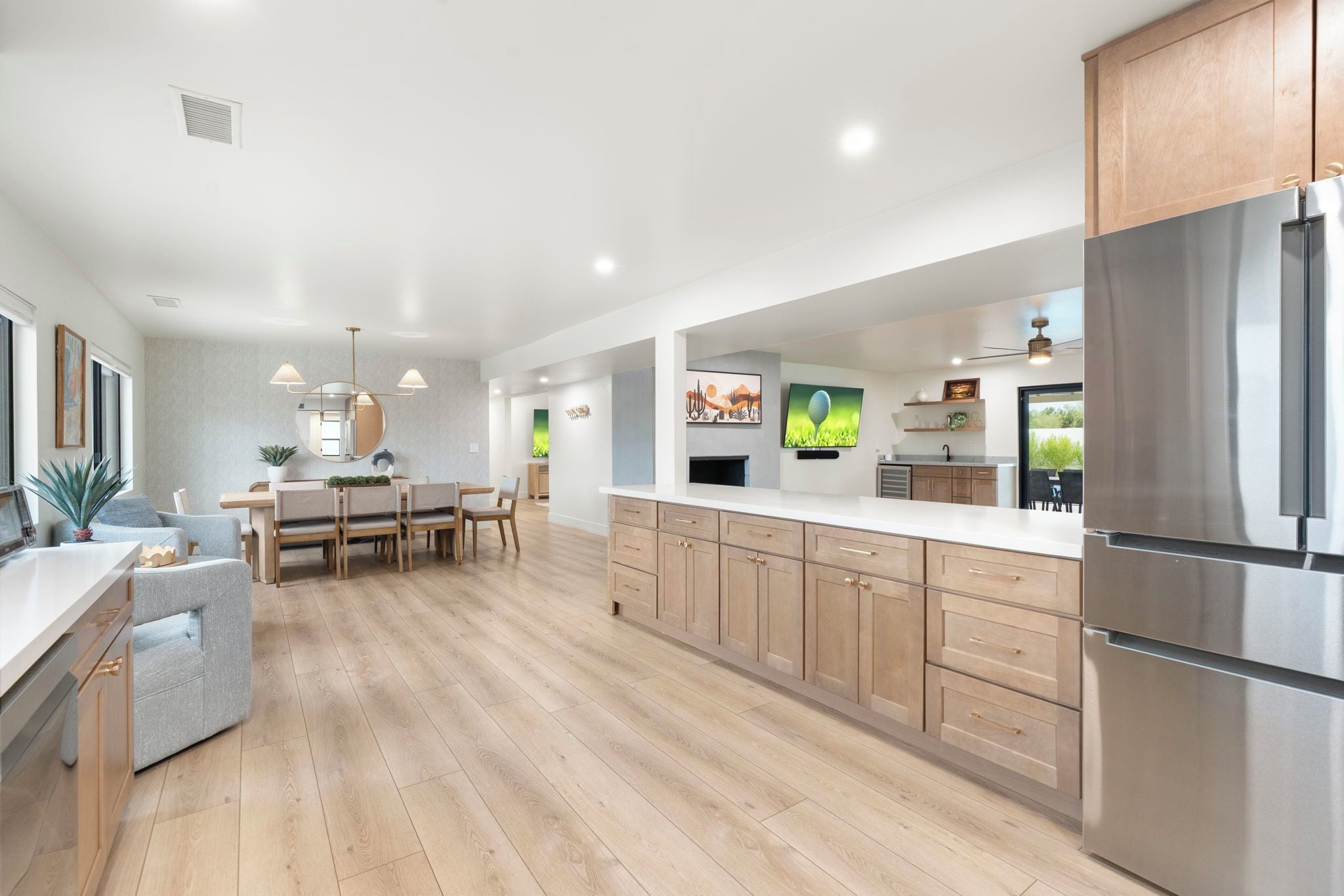 A modern kitchen with wooden cabinets, a stainless steel refrigerator, and a dining area with a table and chairs.
