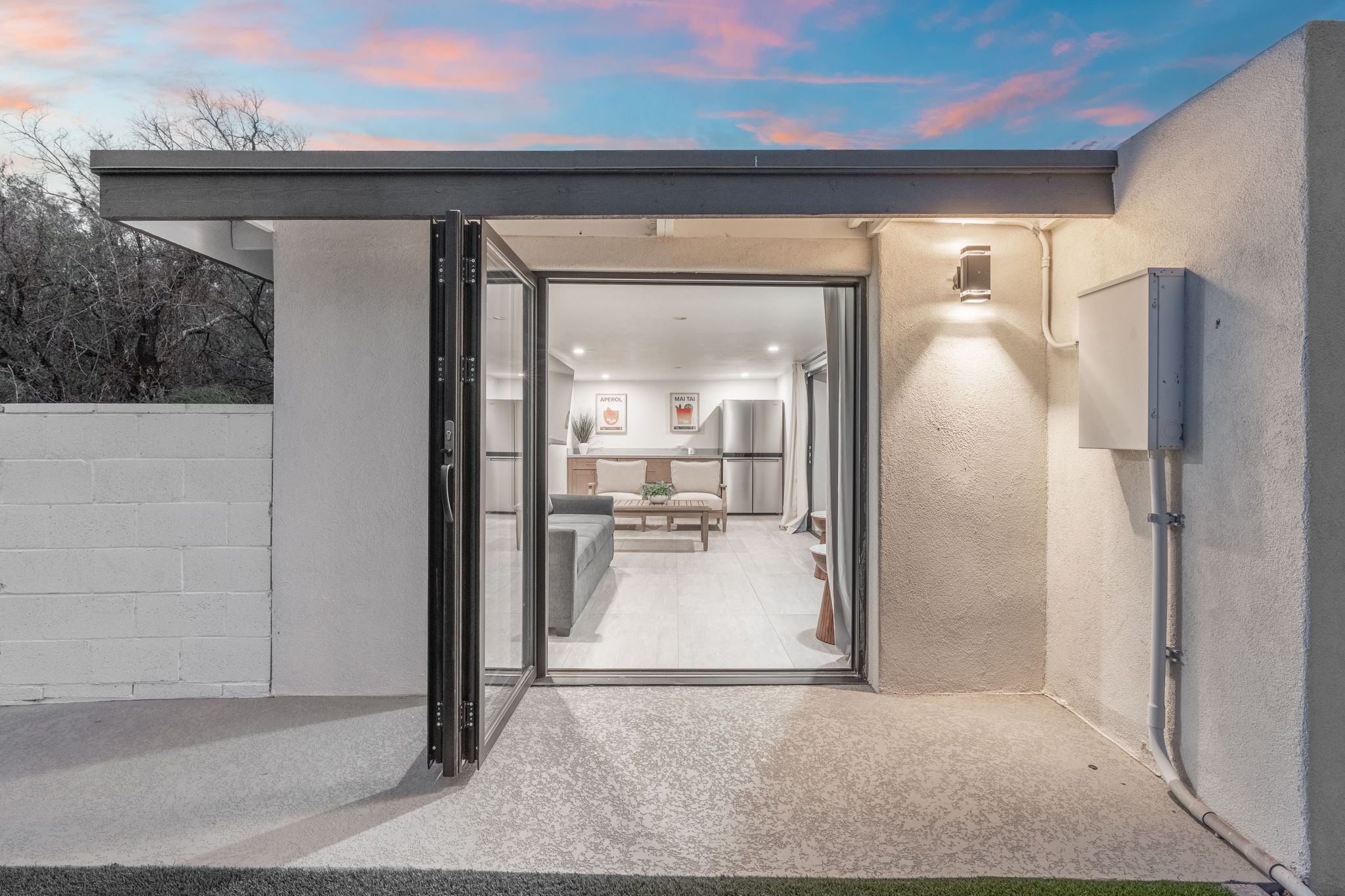 A modern kitchen with a dining area, a large window, and a door leading to an outdoor space.