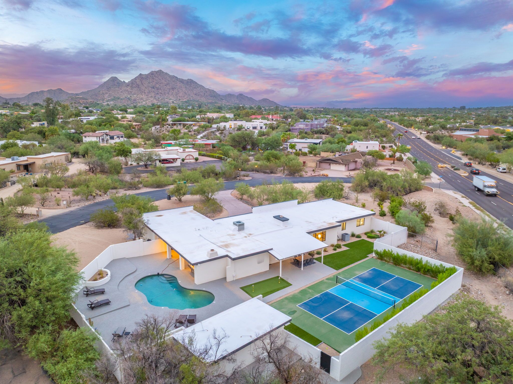 A residential area with a house featuring a swimming pool and tennis court.