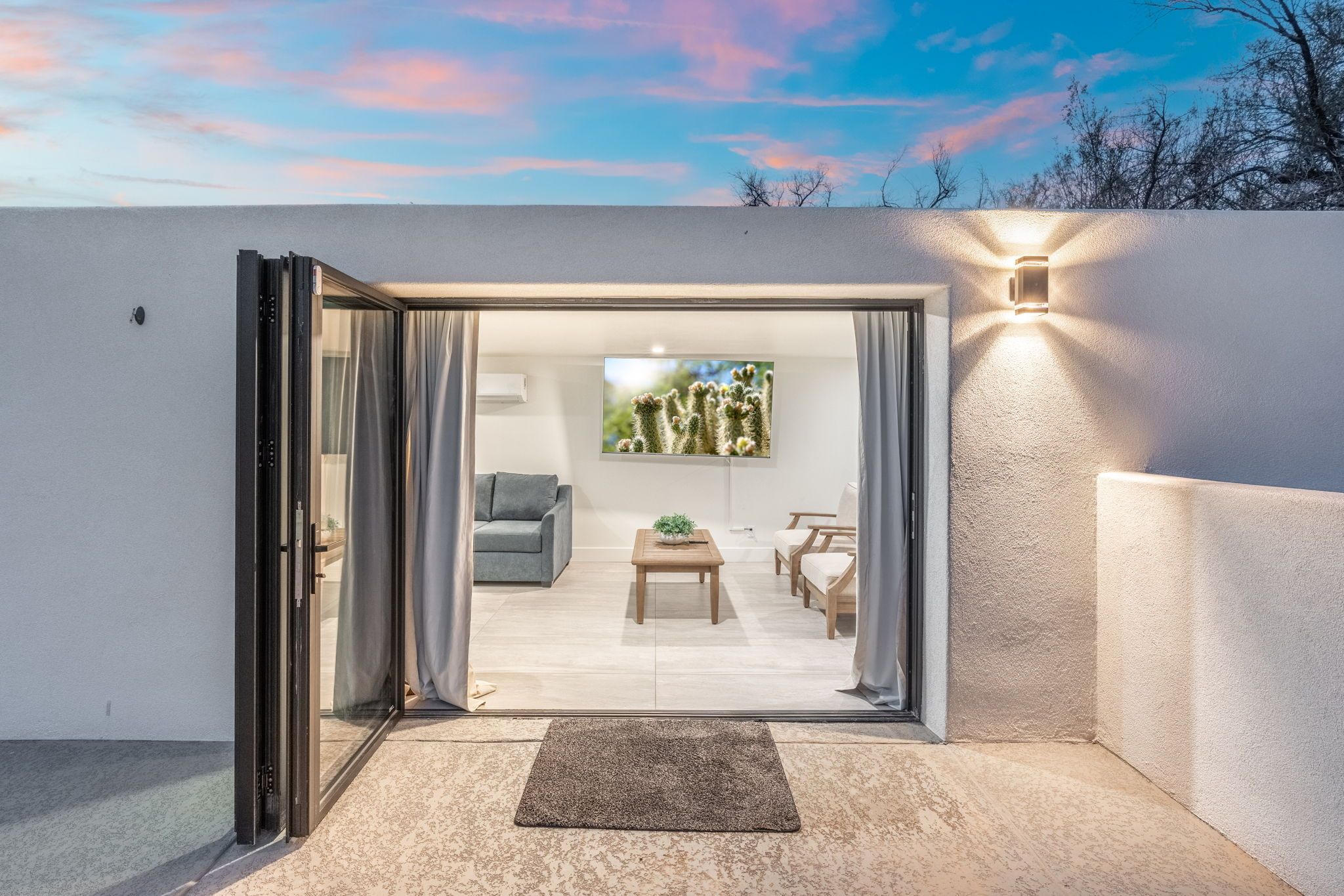 An open door leading to a living area with a sofa, a coffee table, and a TV.