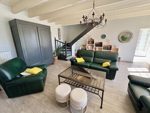 Ein Wohnzimmer mit einem grünen Sofagarnitur, einem Couchtisch und einer Treppe, die zu einer oberen Ebene führt.