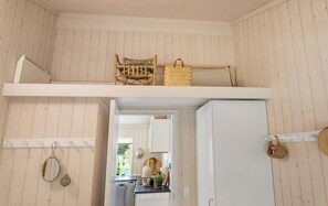 A compact kitchen with a white refrigerator, a wooden chair, and a woven basket.
