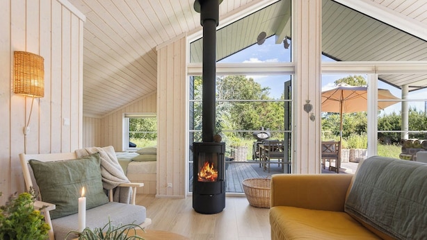 En ombonad inredning med en vedeldad kamin, en sittgrupp och stora fönster.