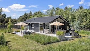 Ett modernt hus med en uteplats, utemöbler och en eldstad i sten.