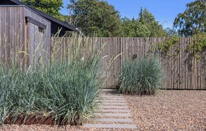 A wooden fence with a pathway leading to a building.