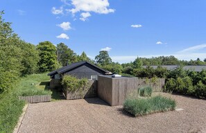 A single-story building with a dark roof, surrounded by a gravel driveway and a wooden fence.