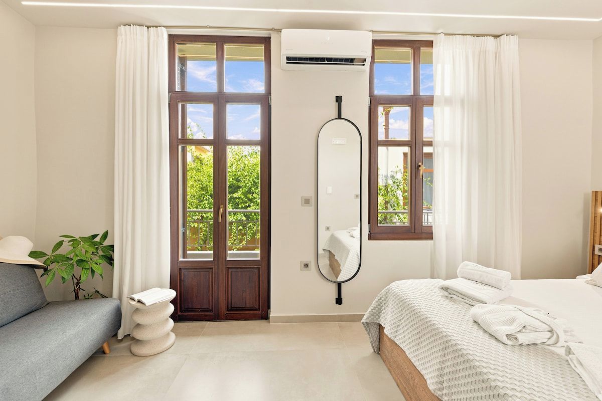 Ein Hotelzimmer mit einem Bett, einem Sofa, einem Spiegel und einem Fenster mit Vorhängen.