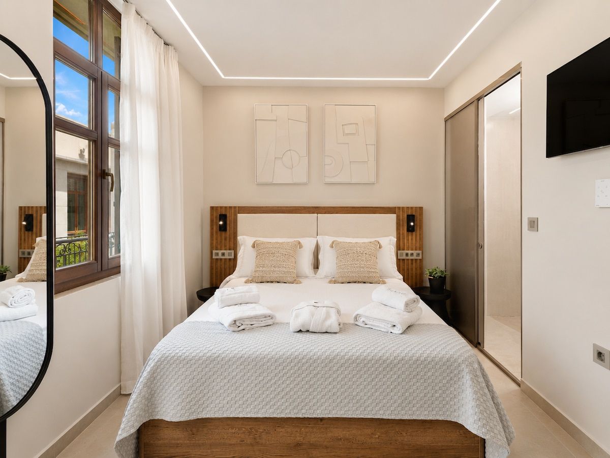 Ein Hotelzimmer mit einem großen Bett, zwei Nachttischen, einem Spiegel und Bildern an der Wand.