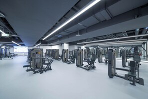 A modern gym with various exercise machines and a large mirror wall.