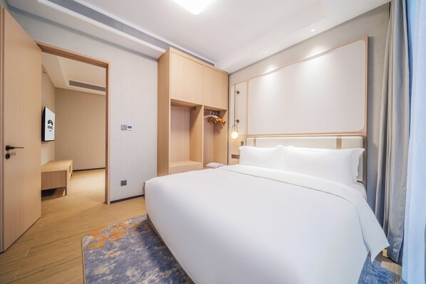 A hotel room with a large bed, a walk-in closet, and a bathroom.