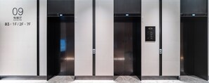 Three elevator doors with a digital display and a sign indicating the elevator number and floor levels.