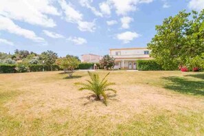 A grassy outdoor area with a building in the background. - 4 Bedroom Villa Lombos with Pool in Porches (Lagoa)
