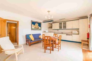 A compact living space with a sofa, dining table, and kitchenette. - 4 Bedroom Villa Lombos with Pool in Porches (Lagoa)