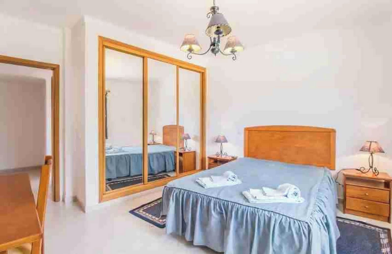 A hotel room with a bed, a wardrobe, a desk, and a chair.