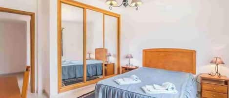 Una habitación de hotel con cama, armario, escritorio y silla.