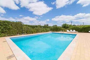 A rectangular swimming pool with a tiled edge, surrounded by a paved area and a hedge. - 4 Bedroom Villa Lombos with Pool in Porches (Lagoa)