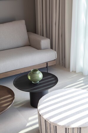 A modern living room with a sofa, a coffee table, and a striped ottoman.