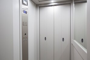 An elevator with a digital display, emergency phone, and a door with a handle.
