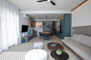 A modern living room with a sofa, coffee table, and a dining area with chairs and a table.