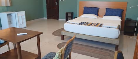 A hotel room with a bed, a desk, a chair, a wardrobe, and a door.