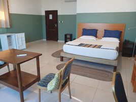 A hotel room with a bed, a desk, a chair, a wardrobe, and a door.