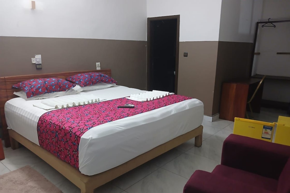 Quarto de hotel com cama, escrivaninha e cadeira.