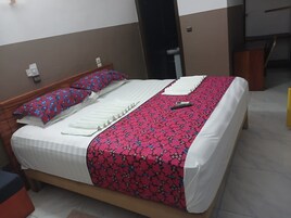 A bed with a white and red patterned bedspread, a pillow, and a remote control on it.