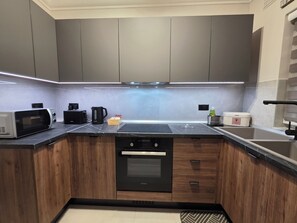 Eine moderne Küche mit grauen Schränken, einer Mikrowelle, einer Kaffeemaschine und einem eingebauten Backofen.