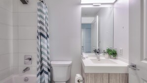 A modern bathroom with a shower, toilet, and sink.