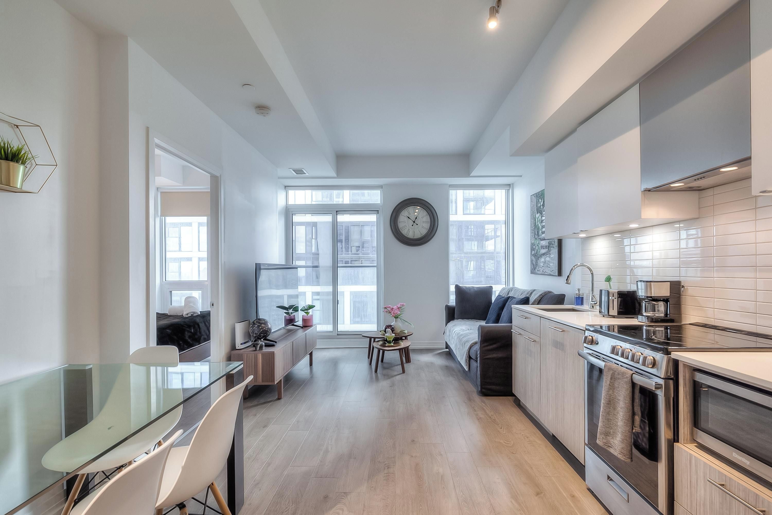 Una cocina moderna con zona de comedor, ventanas amplias y un reloj en la pared.