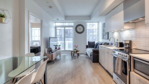 A modern kitchen with a dining area, large windows, and a clock on the wall.