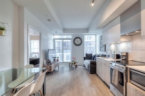 Une cuisine moderne avec un coin repas, de grandes fenêtres et une horloge au mur.