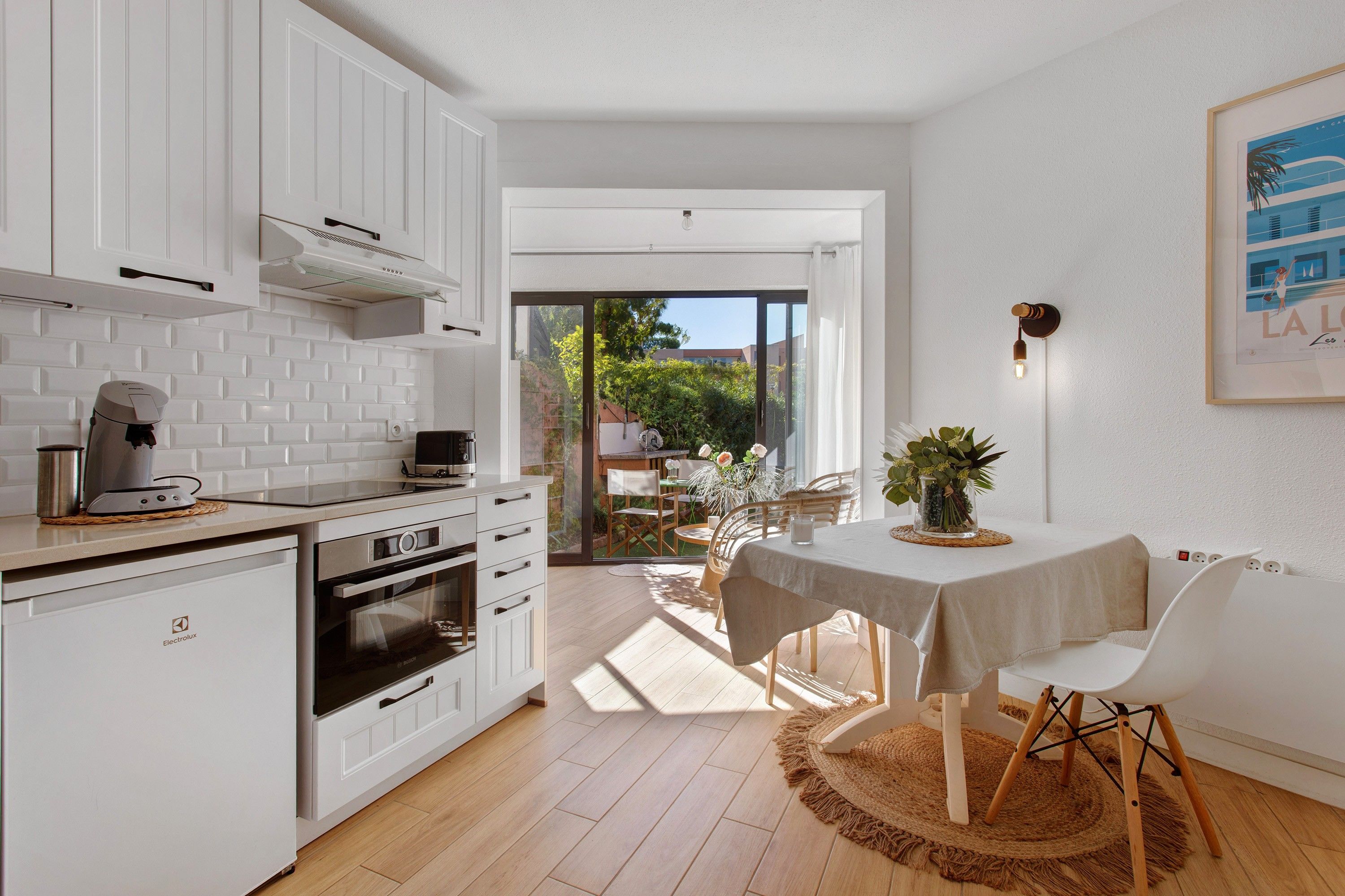 A modern kitchen with white cabinetry, an Electrolux oven, and a coffee machine.