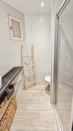 Een badkamer met een houten ladder, een wit toilet en een douchehoek.