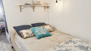 Ett sovrum med en säng, en hylla med dekorativa föremål och en hängande lampa.