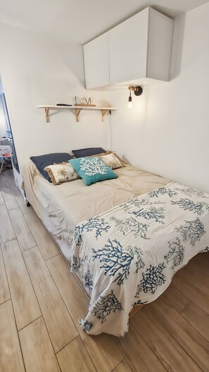 Een slaapkamer met een bed, een plank met decoratieve objecten en een hanglamp.