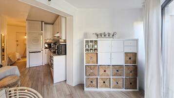Eine moderne Küche mit weißen Schränken, einem Essbereich mit Tisch und Stühlen sowie einem Stauraum mit mehreren Fächern.