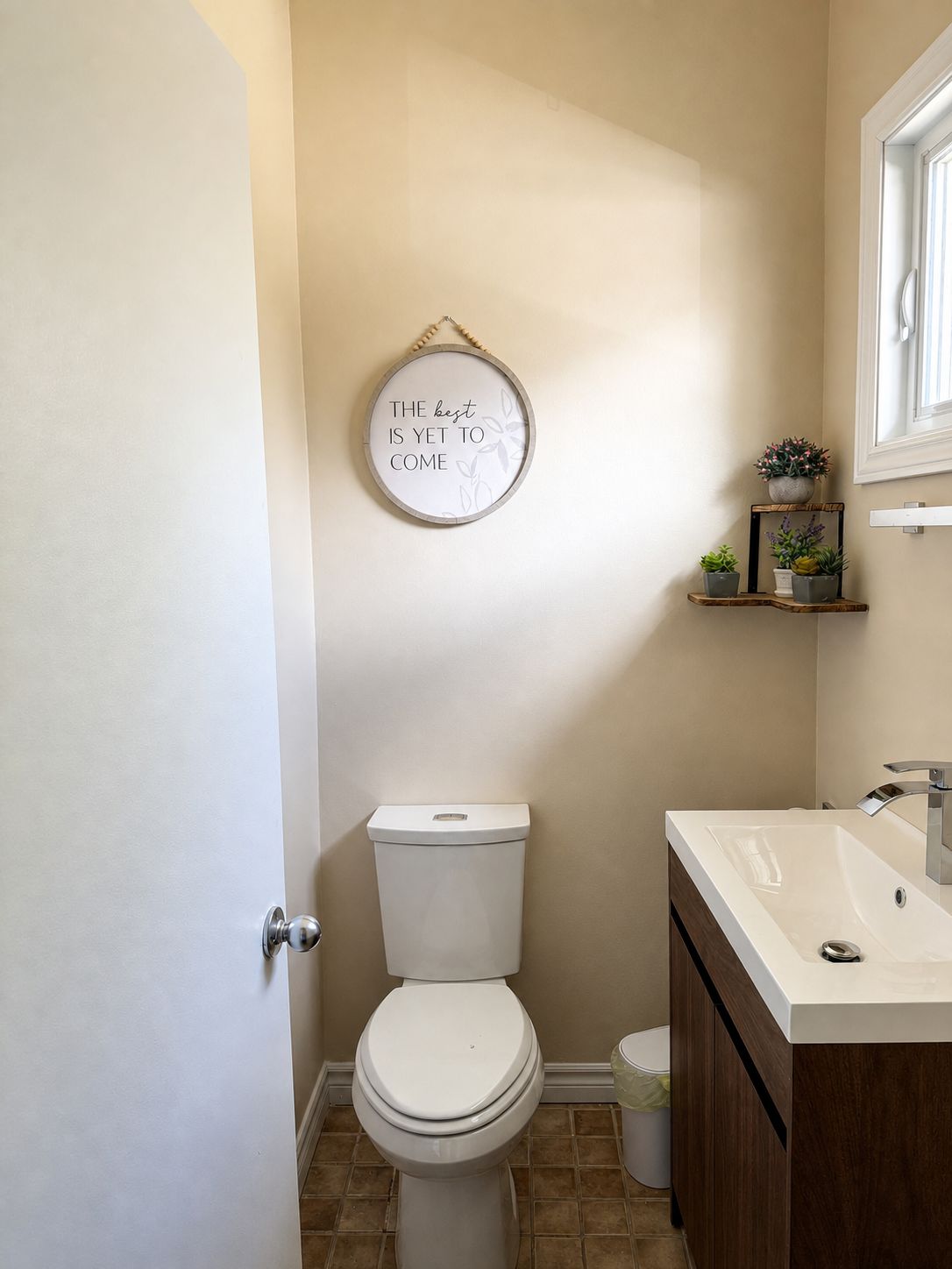 Un baño con inodoro, lavamanos y estante empotrado con plantas.