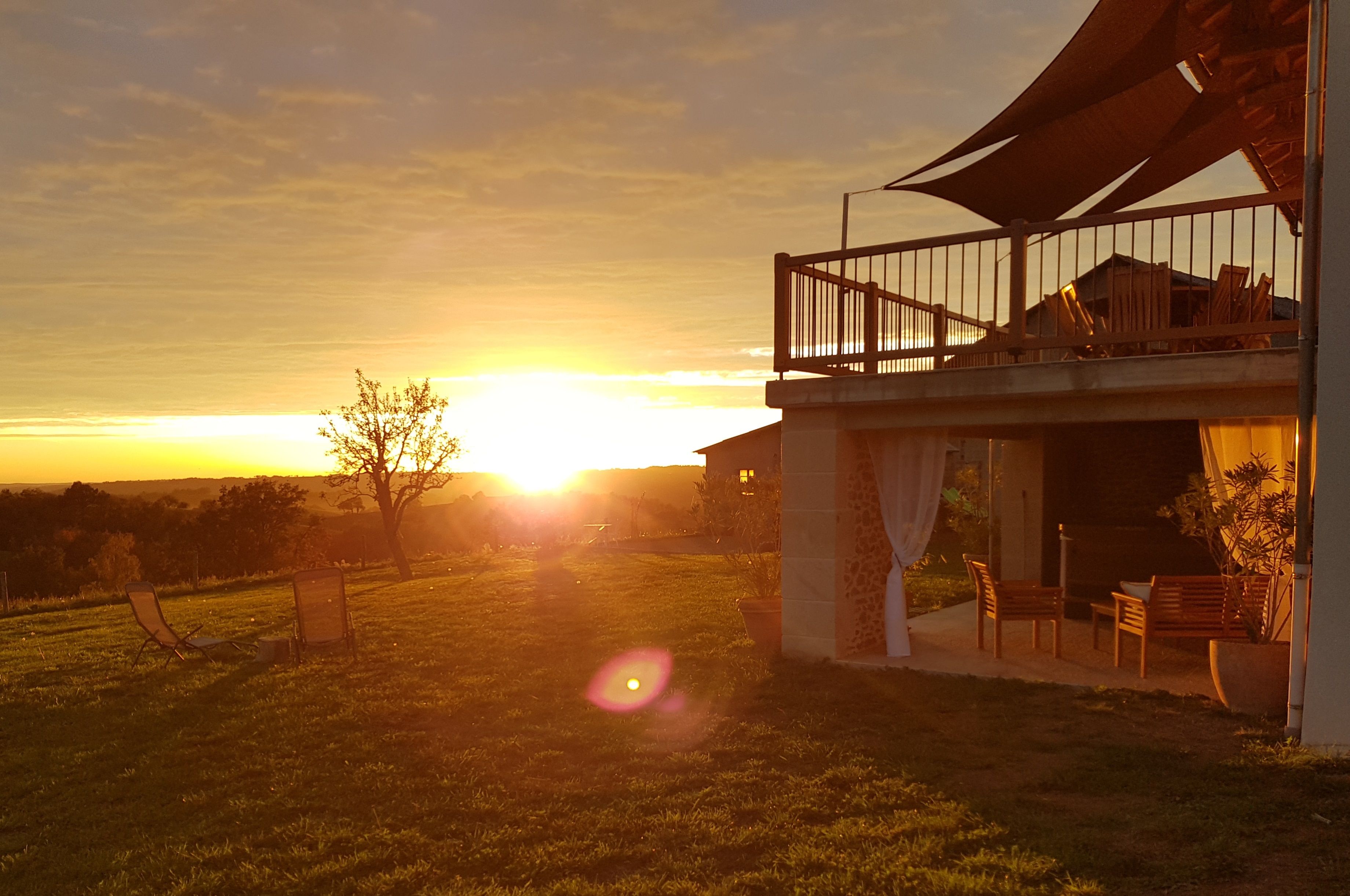 Een huis met een balkon, met uitzicht op een zonsondergang.
