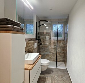 Un bagno moderno con doccia vetrata, lavandino bianco e water.