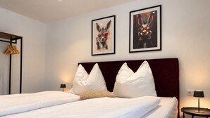 Habitació d'hotel amb llit de matrimoni, dos almoinos, una capçalera, dues làmpades de paret i dues imatges emmarcades.