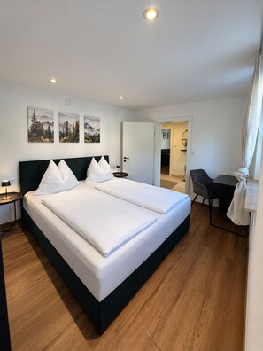 Una camera d'albergo con un letto grande, una scrivania e una sedia. Alle pareti sono presenti tre quadri.