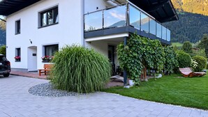 Una casa moderna de dos pisos amb un balcó, una entrada per cotxes i un jardí ben cuidat.