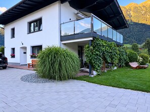 Una moderna casa a due piani con un balcone, una strada privata e un giardino curato.