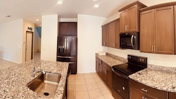 A modern kitchen with granite countertops, stainless steel appliances, and wooden cabinets.