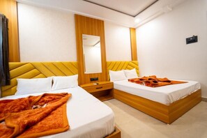 Habitació d'hotel amb dos llits, un amb fusta decorativa, un mirall i una tauleta de nit.