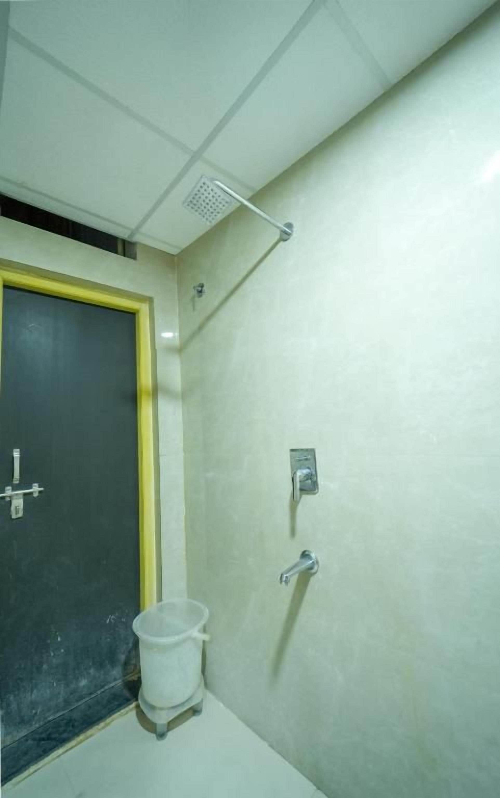 Un baño con ducha, inodoro y cubo de basura.
