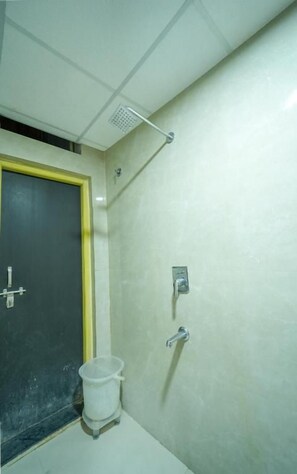 Un baño con ducha, inodoro y cubo de basura.