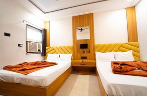 Habitació d'hotel amb dos llits, un panell de fusta al capçal, un mirall, un ventilador de sostre i un aparell d'aire condicionat.